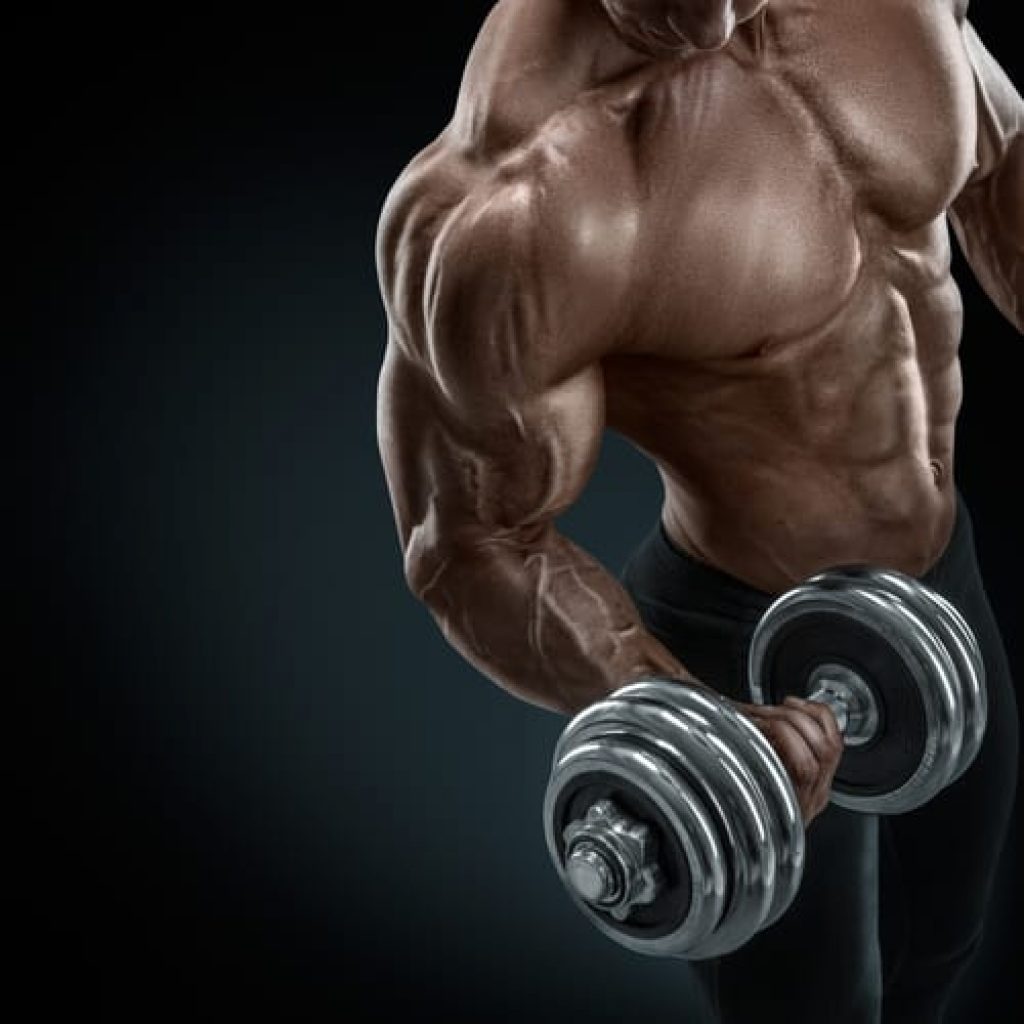 Closeup of a handsome power athletic guy male bodybuilder doing exercises with dumbbell. Fitness muscular body on dark background. muscle building